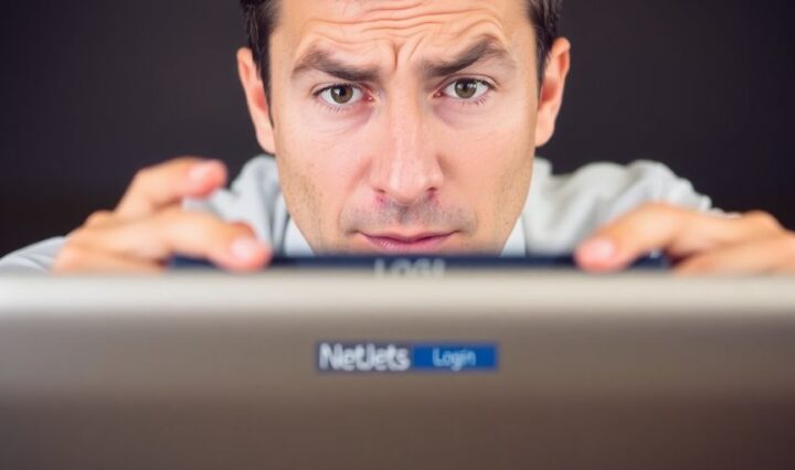 Person frustrated at a laptop screen displaying the NetJets login page.